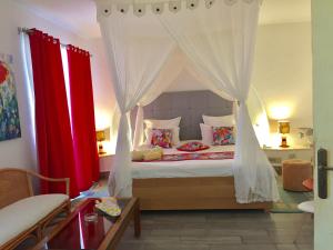 迈来亚Hotel Djerba Orient的一间卧室配有一张带红色窗帘的天蓬床