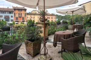 代森扎诺-德尔加达披若斯卡夫酒店的庭院配有桌椅和遮阳伞。