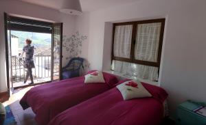 蒙地卡罗埃尔莫利诺德尔阿布罗的一间卧室配有一张紫色的床,其中一位女士从窗户走出去