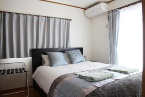 东京HAMA HILLS Shinjuku的一间卧室配有一张带蓝色枕头的床和一扇窗户。