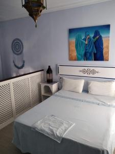 桑卢卡尔-德巴拉梅达El apartaito的卧室配有一张白色床,墙上挂有绘画作品