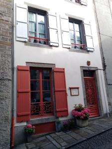 格朗维尔La Maison de Juliette的白色的建筑,有红色百叶窗和鲜花
