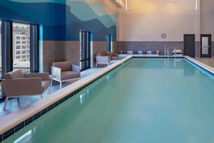 印第安纳波利斯Hyatt House Indianapolis Downtown的游泳池,酒店客房带椅子