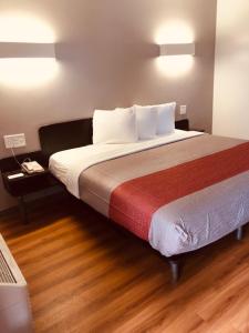 奥古斯塔Motel 6-Augusta, GA - Fort Gordon的一间卧室设有一张大床,铺有木地板