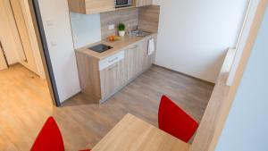 梅明根A2 Boarding House Memmingen的一个带红色椅子和桌子的小厨房