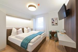 Schwadorf23-hotel的一间卧室配有一张带电视和书桌的床。