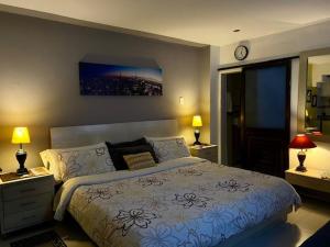 巴兰基亚Apartaestudio El Lugar Ideal Cra. 62 #74-143.的一间卧室配有一张床、两盏灯和一个时钟