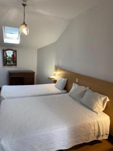 科英布拉Guesthouse Lusa Atenas的一间卧室配有两张带白色床单的床