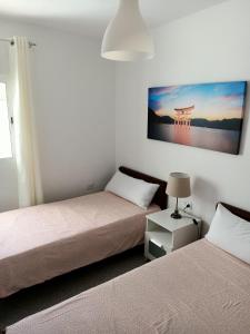 格拉纳迪利亚德亚沃纳Casa Mary的一间卧室设有两张床,墙上挂着一幅画