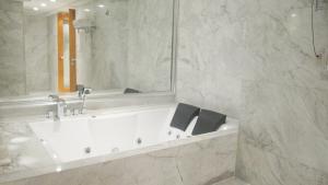 南京Glarun Jinling Hotel的浴室设有白色浴缸及镜子