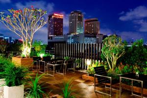 曼谷皇家公主兰朗酒店 - SHA Extra Plus的一个带桌椅的屋顶露台,享有城市天际线
