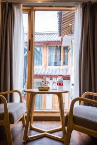 丽江丽江云起度假客栈(束河抒心会馆)的窗前的一张桌子和两把椅子