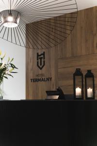 乌涅尤夫Hotel Termalny的酒店终端上有两个蜡烛和墙上的标志