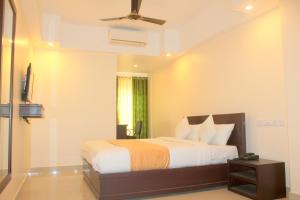 德里久尔Aura Residency的一间卧室配有一张床和吊扇