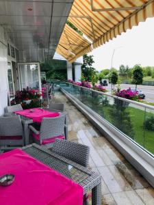 沃莱尼德蒙泰Hotel Afrodita -Valenii De Munte的阳台餐厅,配有粉红色的桌椅