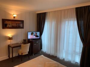 Želiezovce伊甸园宾馆的酒店客房设有电视和桌椅