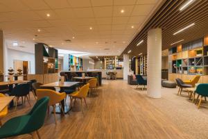 布达厄尔什Holiday Inn Budapest-Budaörs, an IHG Hotel的自助餐厅内带桌椅的餐厅