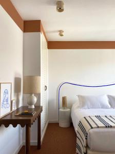 胡安莱潘Hôtel Le Sud的一间卧室配有一张床和一张带台灯的桌子