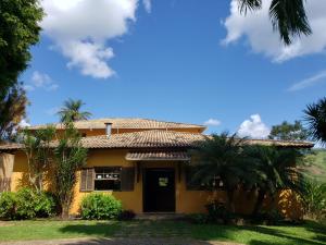 Simão PereiraHotel Fazenda Minas Real的棕榈树前方的黄色房子