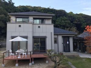KashūMIKOTO HOUSE的房屋设有1个带桌子和遮阳伞的甲板