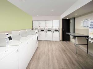 梅里尔维尔WoodSpring Suites Merrillville的洗衣房配有白色橱柜和桌子