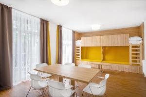 希欧福克Szent Bernadett Családi Apartmanház的一间带木桌和白色椅子的用餐室