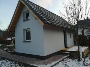 卡尔帕奇Domek Bobrowe Zacisze w Górach Sokolich的雪中带黑色屋顶的白色房子
