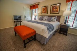 布鲁斯特布鲁斯特格林VRI度假村的一间卧室配有一张带橙色凳子的床和电视。