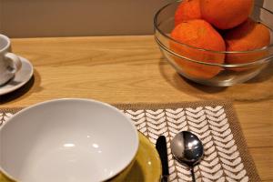 法鲁Cardeal Suites & Apartments的一张桌子,上面放着一碗橙子,盘子和勺子