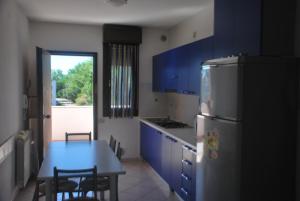 罗索利纳马雷Acquasmeralda appartamento 01的厨房配有蓝色橱柜、桌子和冰箱。