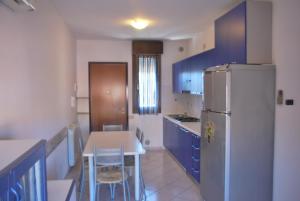 罗索利纳马雷Acquasmeralda appartamento 01的厨房配有冰箱和桌椅