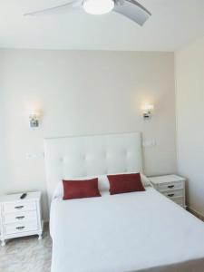 桑亨霍Hotel costa mar的卧室配有白色的床和红色枕头
