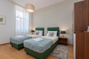 普拉Aurora Rooms B&B Pula的一间卧室设有两张绿化床和一面墙