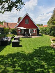 利费尔德Lekker Plekje Achterhoek的院子里的红色谷仓,配有沙发和椅子