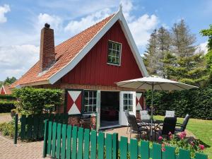 利费尔德Lekker Plekje Achterhoek的红色的房子,配有桌子和雨伞
