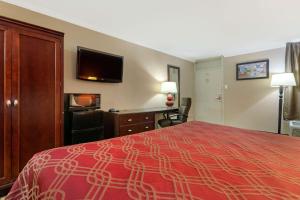 海恩斯维尔Econo Lodge Near Fort Stewart, Bar, Restaurant, Laundry Facility的酒店客房配有一张床、一张书桌和一台电视。