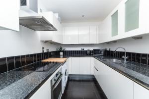泰恩河畔纽卡斯尔Newcastle Penthouse - Sleeps 8 - City Centre - Free Parking - City Views的厨房配有白色橱柜和黑色台面