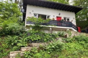 维安登The Vianden Cottage - Charming Cottage in the Forest的带阳台的房屋,设有红色门