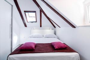 杜布罗夫尼克Apartman Roseta的一张白色的床,上面有两个紫色枕头