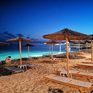 尼基季Nikiti Modern Villa的海滩上设有桌子和遮阳伞,还有大海