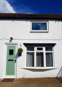 大德里菲尔德Ladybird Cottage, Dog Friendly, Couples or Small families, Yorkshire Wolds - Countryside and Coast的白色的房子,设有绿门和窗户