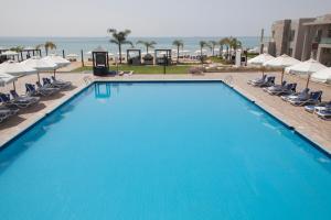 艾因苏赫纳Elite Residence & Aqua Park的一个带椅子和遮阳伞的大型蓝色游泳池