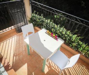 昂蒂布Orangeraie du Cap d'Antibes的阳台上配有一张白色的桌子和两把椅子