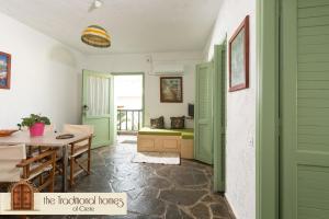 伊罗达Elounda Collection Apartments的配有绿色百叶窗的门和桌椅的房间