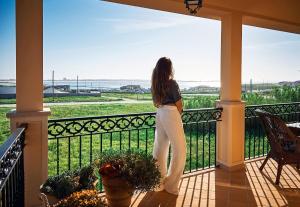 巴勒尔Silver Coast Beach Residence的站在一个眺望海洋的阳台上的女人