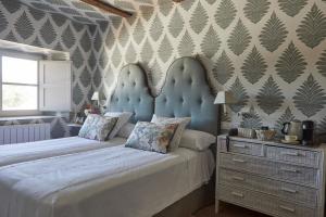 塞哥维亚Hotel Caserio Aldeallana的一间卧室配有两张带蓝色床头板的床和梳妆台。