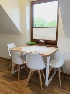 什恰夫尼察Apartamenty Kornaje的餐桌、白色椅子和窗户