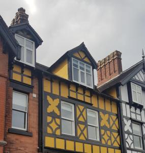 彻奇斯特雷顿Victoria House的黄色和黑色的建筑,设有白色的窗户