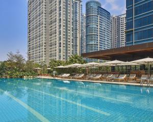 马尼拉Grand Hyatt Manila的一个带椅子和遮阳伞的游泳池以及建筑