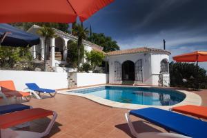 孔佩塔Villa Andalucia的房屋旁的游泳池配有椅子和遮阳伞